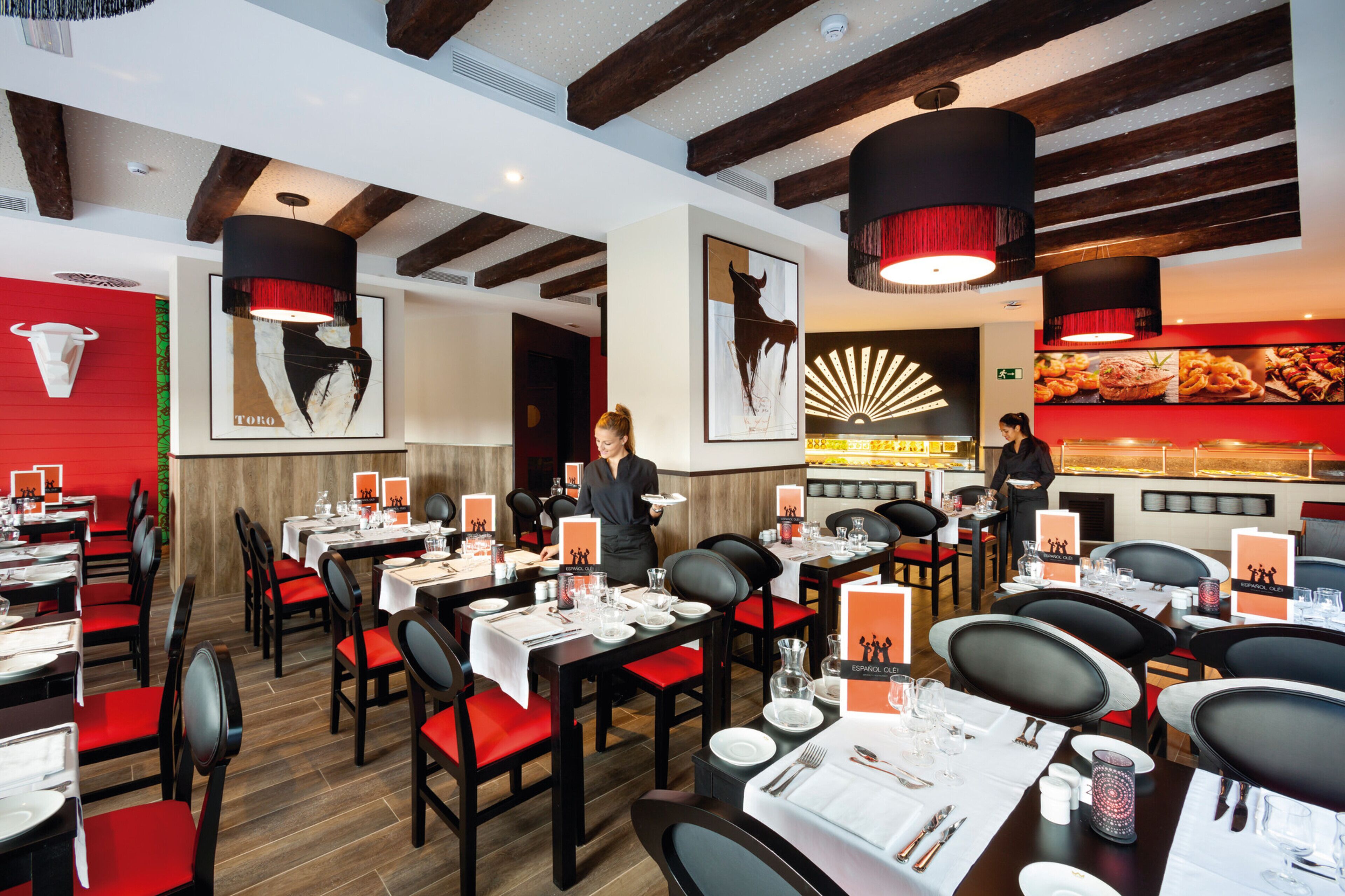 Un restaurant avec des tables dressées pour le service, un comptoir où sont exposés les plats, et un espace bar.