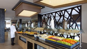 Zona de bufé con diversas opciones de comida y un chef.