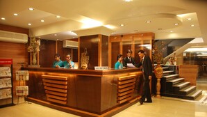 A reception desk with a sign reading "RECEPTION" and a man standing beside it. - Hotel Pan Asia Continental (Kolkata)