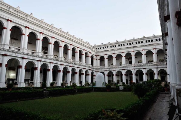 Um edifício grande e branco com várias arcadas e um pátio central.