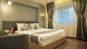 A modern hotel room with a large bed, bedside tables, a desk, and a chair. - Hotel Pan Asia Continental (Kolkata)