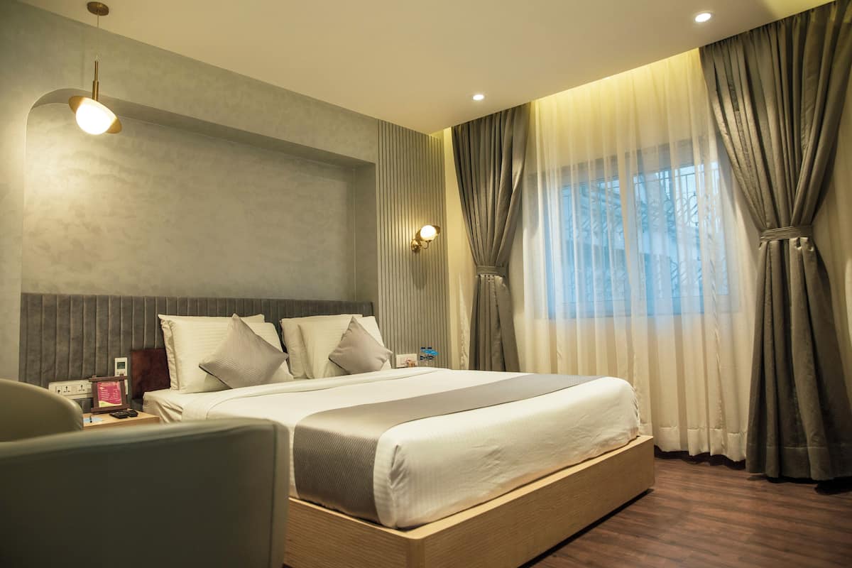 A modern hotel room with a large bed, bedside tables, a desk, and a chair.