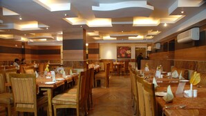 A restaurant with multiple dining tables and chairs, arranged in a spacious layout. - Hotel Pan Asia Continental (Kolkata)