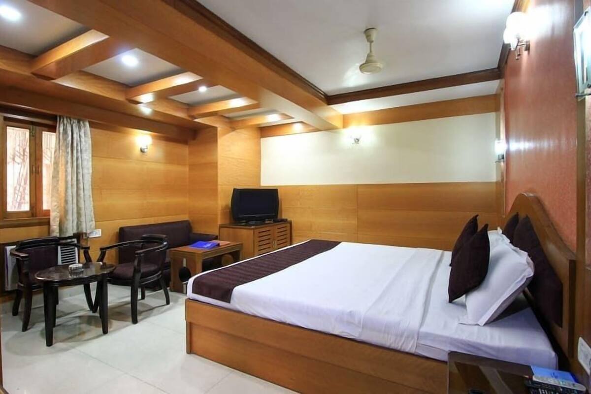 A hotel room with a bed, a desk, a chair, a television, and a window with curtains.
