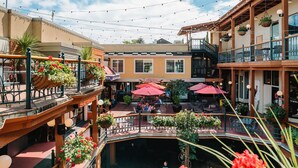 A courtyard with outdoor seating, string lights, and hanging planters. - Inn at the 5th (Eugene)