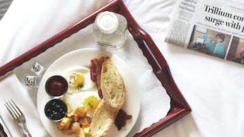 A tray with breakfast items including toast, eggs, and potatoes, alongside a newspaper.