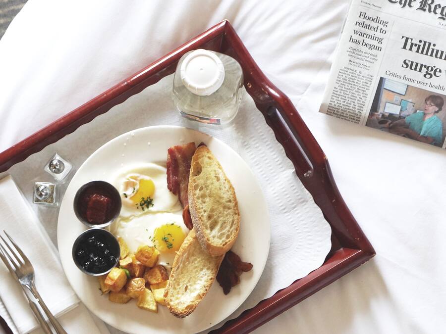 A tray with breakfast items including toast, eggs, and potatoes, alongside a newspaper.