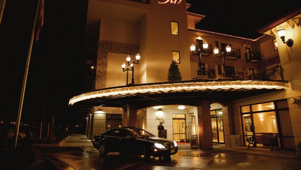 A hotel entrance with a car parked in front, a covered walkway, and a sign reading "Inn at the 5th". - Inn at the 5th (Eugene)