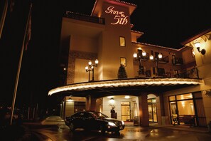 Entrada de un hotel con un automóvil estacionado frente a él, un corredor cubierto y un letrero que dice "Inn at the 5th".