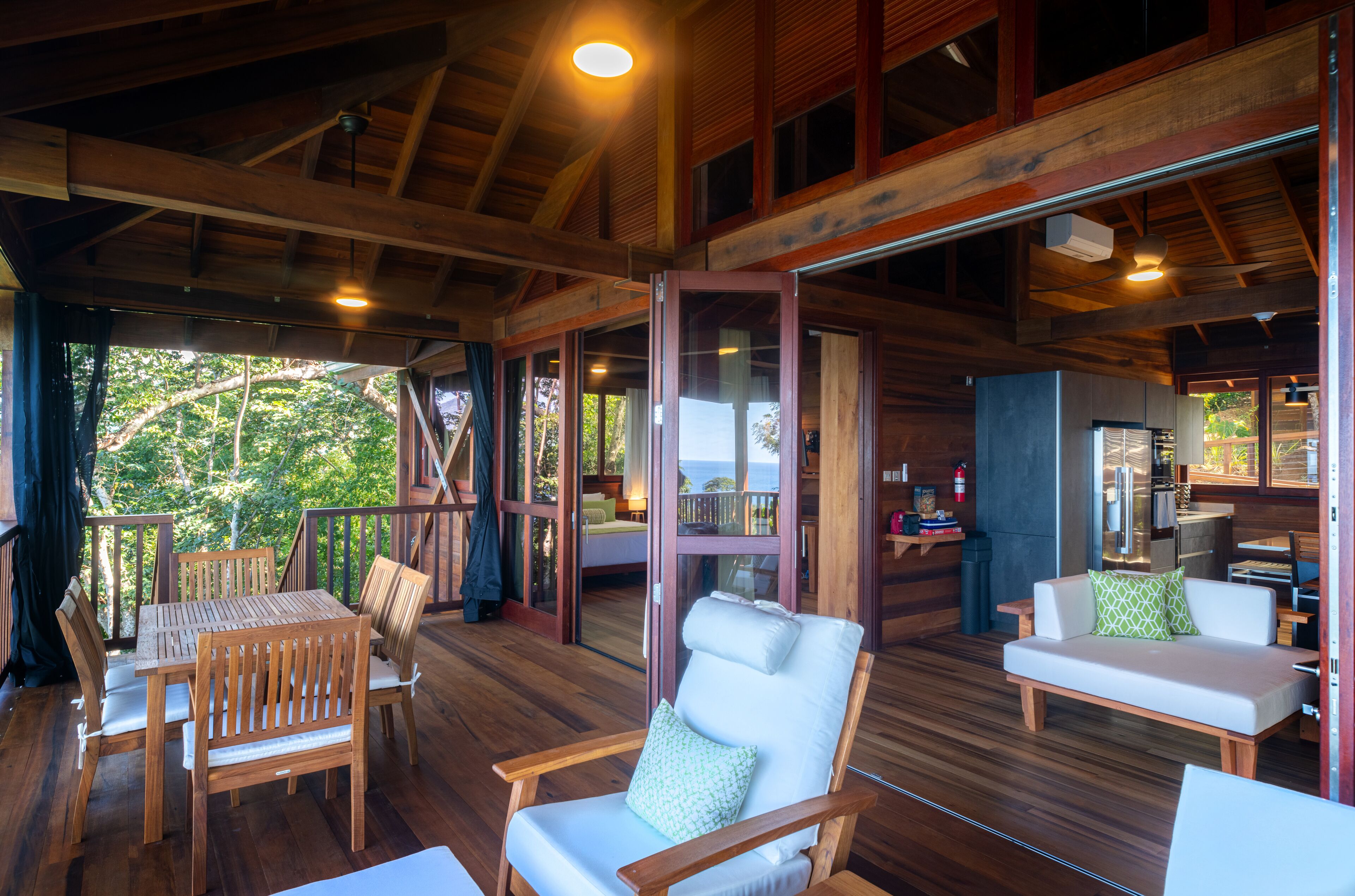 A wooden deck with a table and chairs, a sofa, and a view of the outdoors.