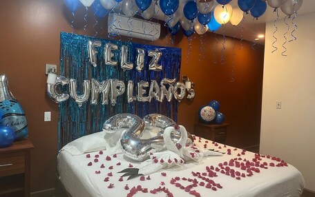A room decorated for a birthday celebration with balloons, a cake, and a banner that reads "Feliz Cumpleaños".