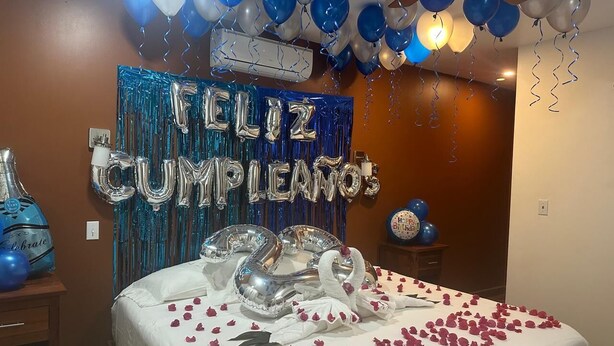 A room decorated for a birthday celebration with balloons, a cake, and a banner that reads "Feliz Cumpleaños". - Venus Hotel (San Ignacio)