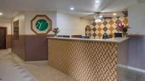 A reception area with a check-in counter, a logo on the wall, and a ceiling fan. - Venus Hotel (San Ignacio)