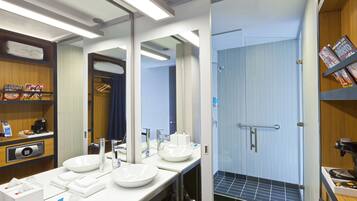 A modern bathroom with two sinks, a large mirror, and a shower area.