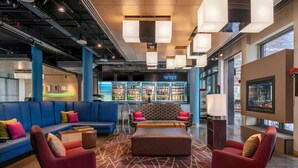 Een moderne lobby met een bar, zitgedeelte en een groot scherm.