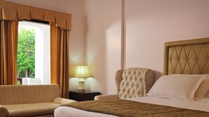 Ein Hotelzimmer mit Bett, Stuhl, Nachttisch und einem fenster mit Vorhängen.