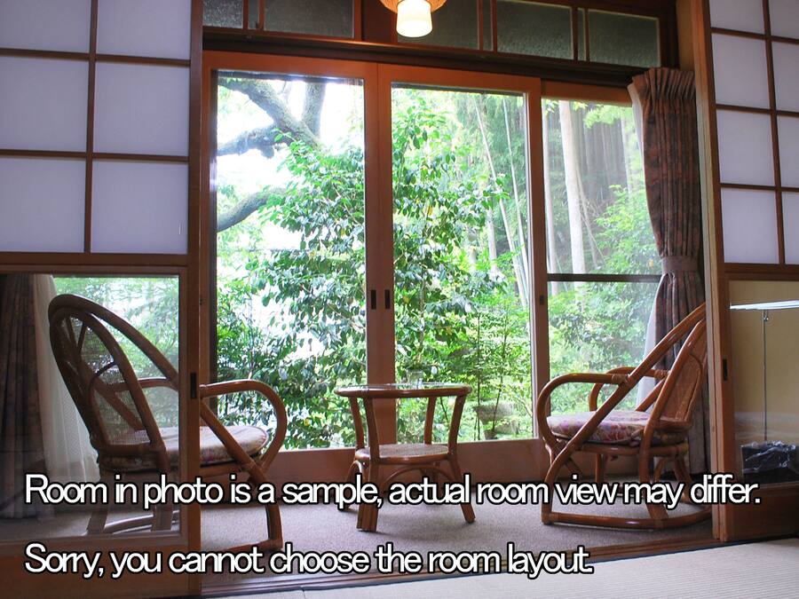 A room with a large window, two wicker chairs, and a small table.