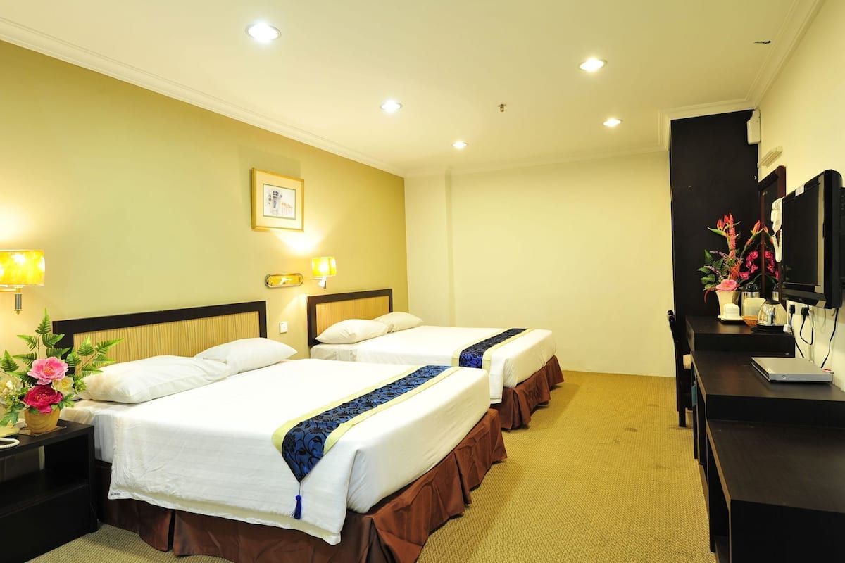 A hotel room with two beds, a desk, a television, and a framed picture on the wall.