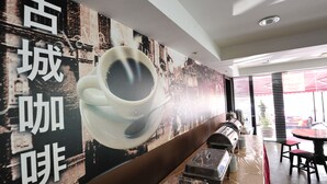 Interieur van een koffiezaak met een grote muurschildering, een koffiekop en een buffet.