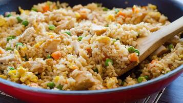 A close-up of a stir-fried rice dish with vegetables and chicken.