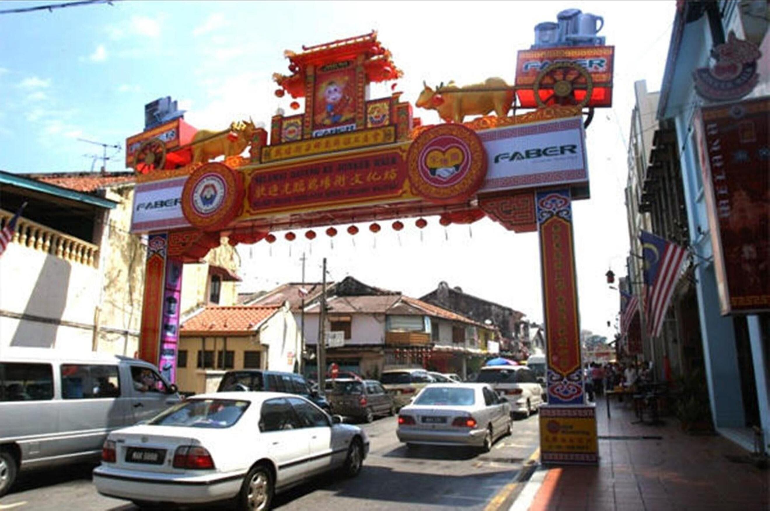 A street with cars and a colorful archway with traditional decorations.