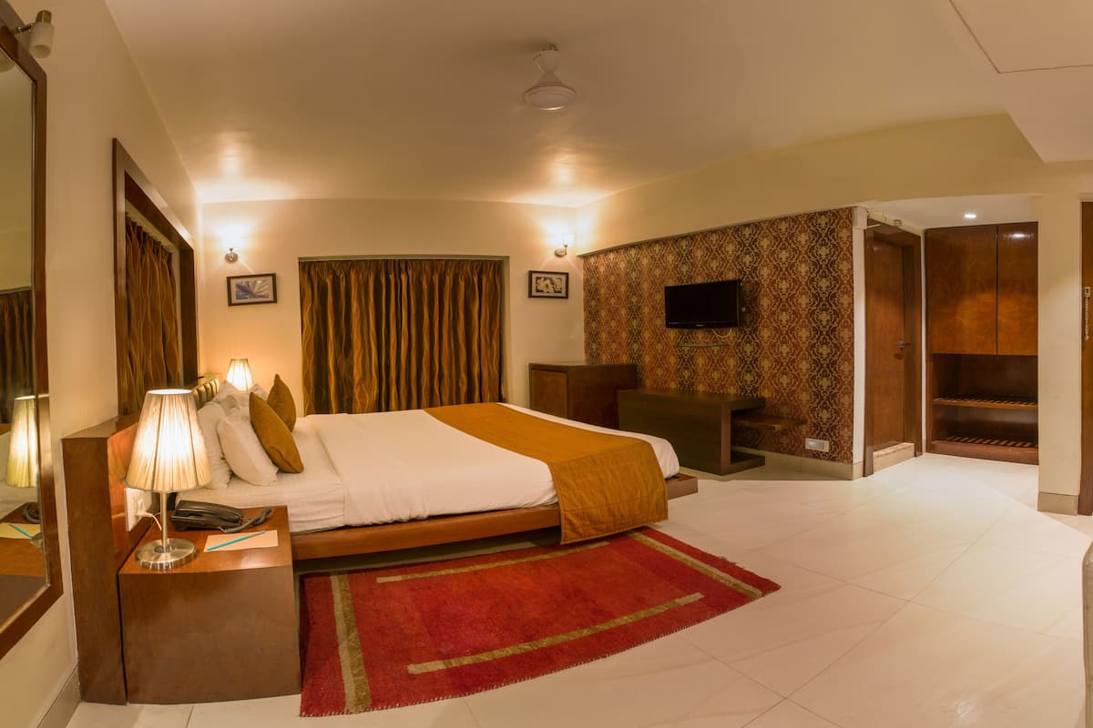 A hotel room with a bed, bedside table, lamp, and a TV.