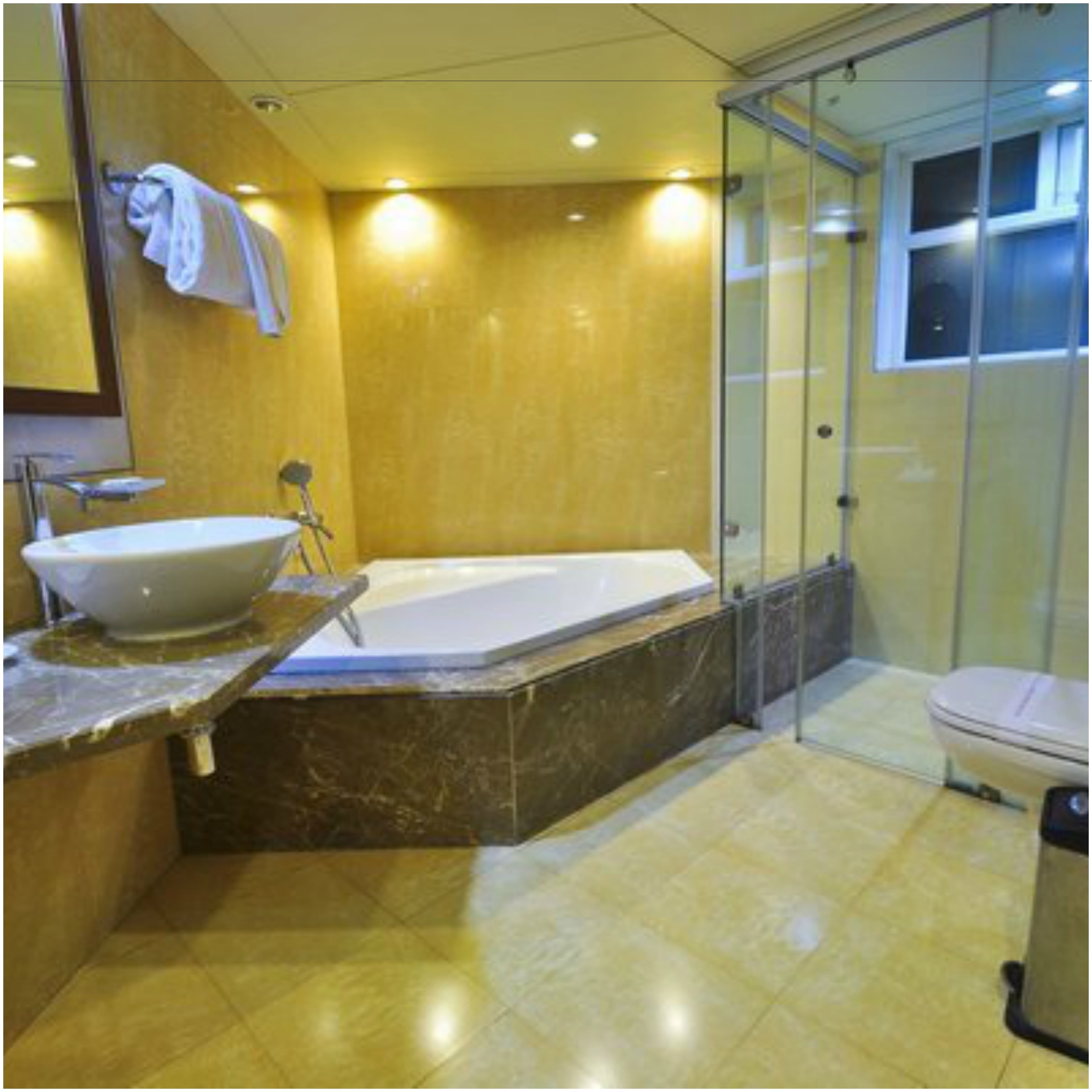 A bathroom with a marble sink, a bathtub, and a glass-enclosed shower.