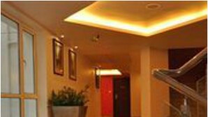 A hotel lobby with a polished floor, a staircase, and a red door. - Hotel Kempton (Kolkata)
