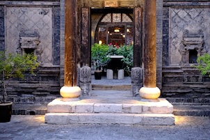 An entrance with stone columns, a tiled floor, and a view of a building with traditional design elements.