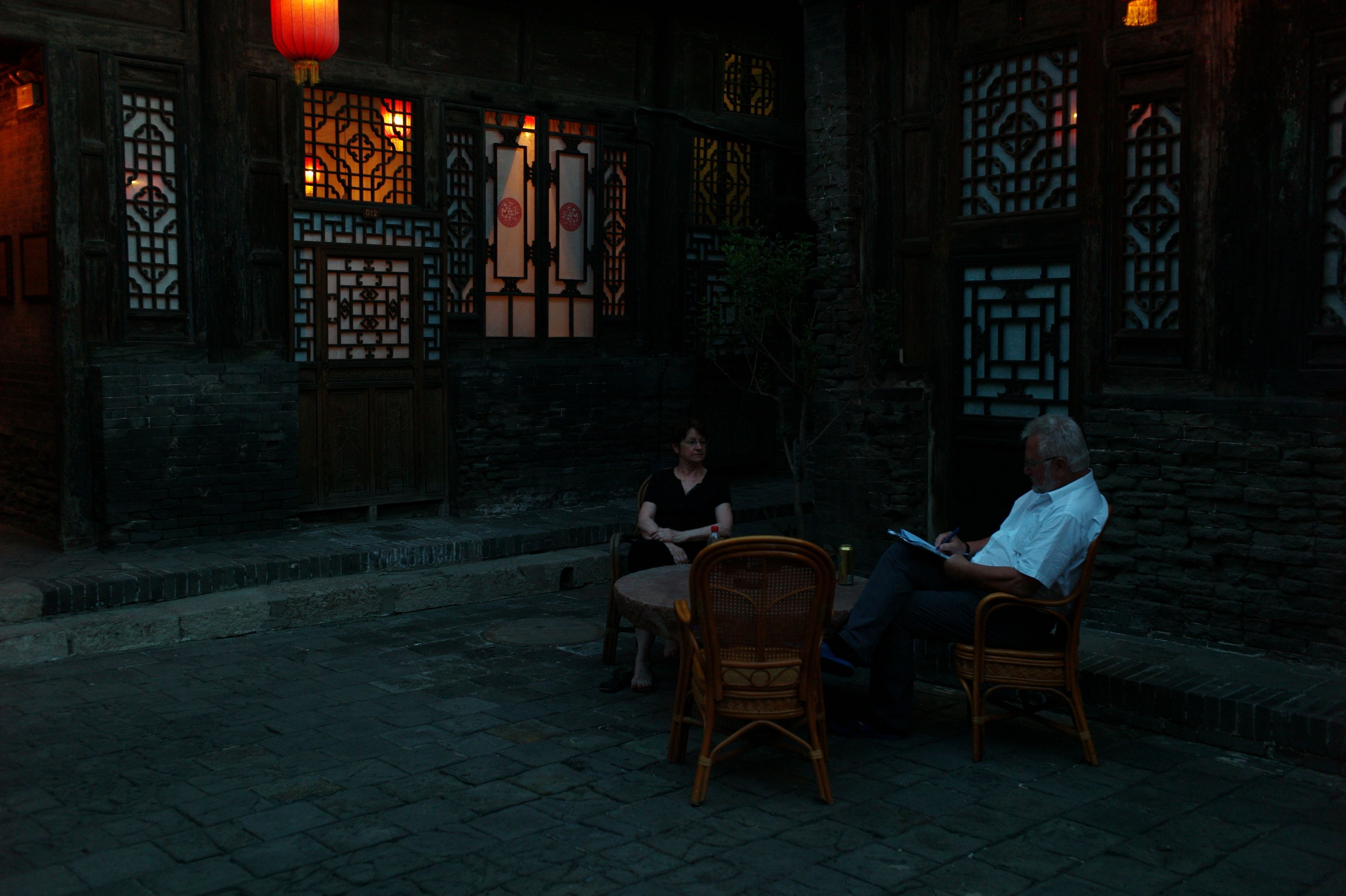 An outdoor seating area with traditional wooden furniture and a stone-paved floor.