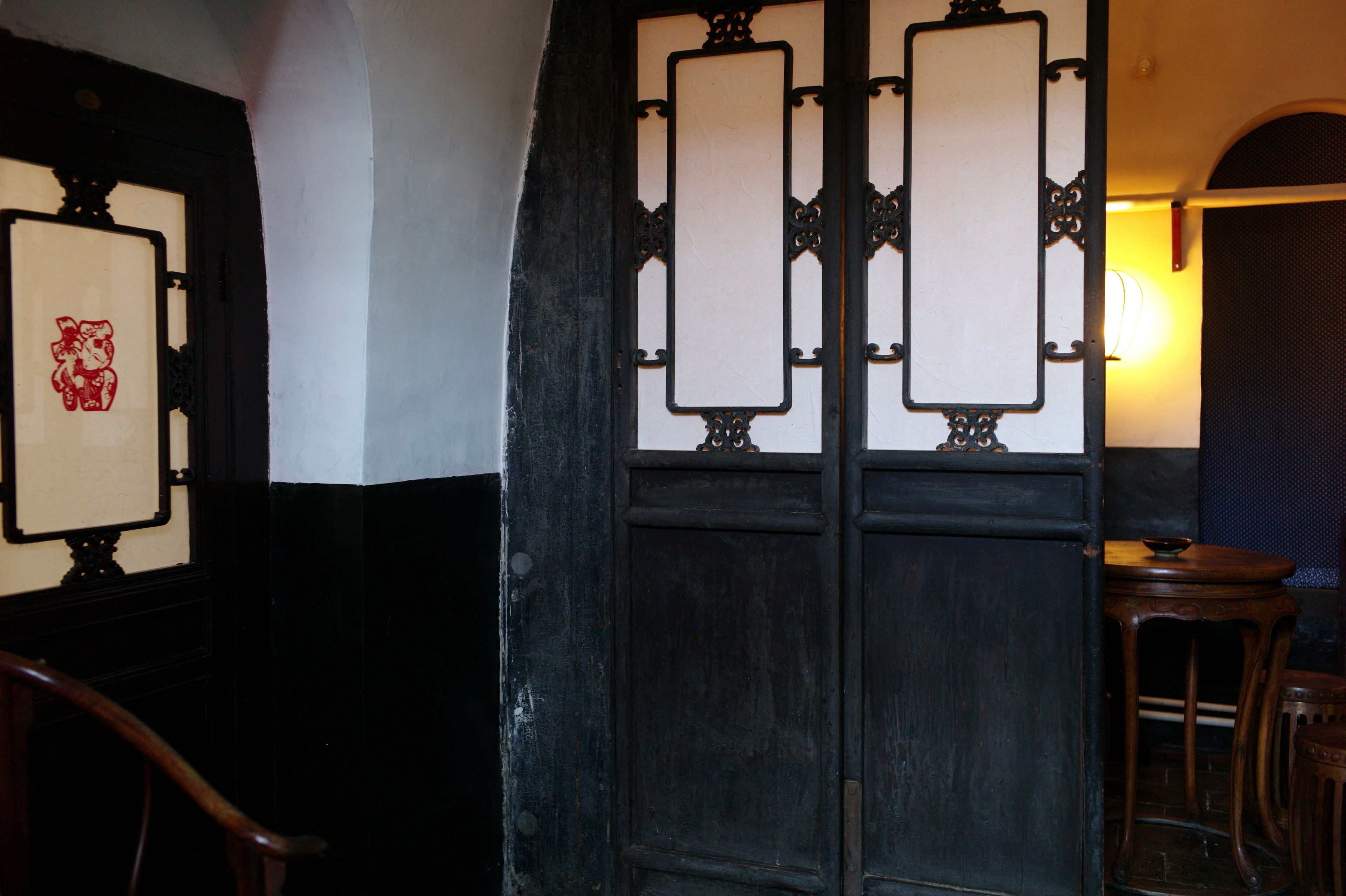 A traditional room with a dark wooden door, a small table with a bowl, and a chair.