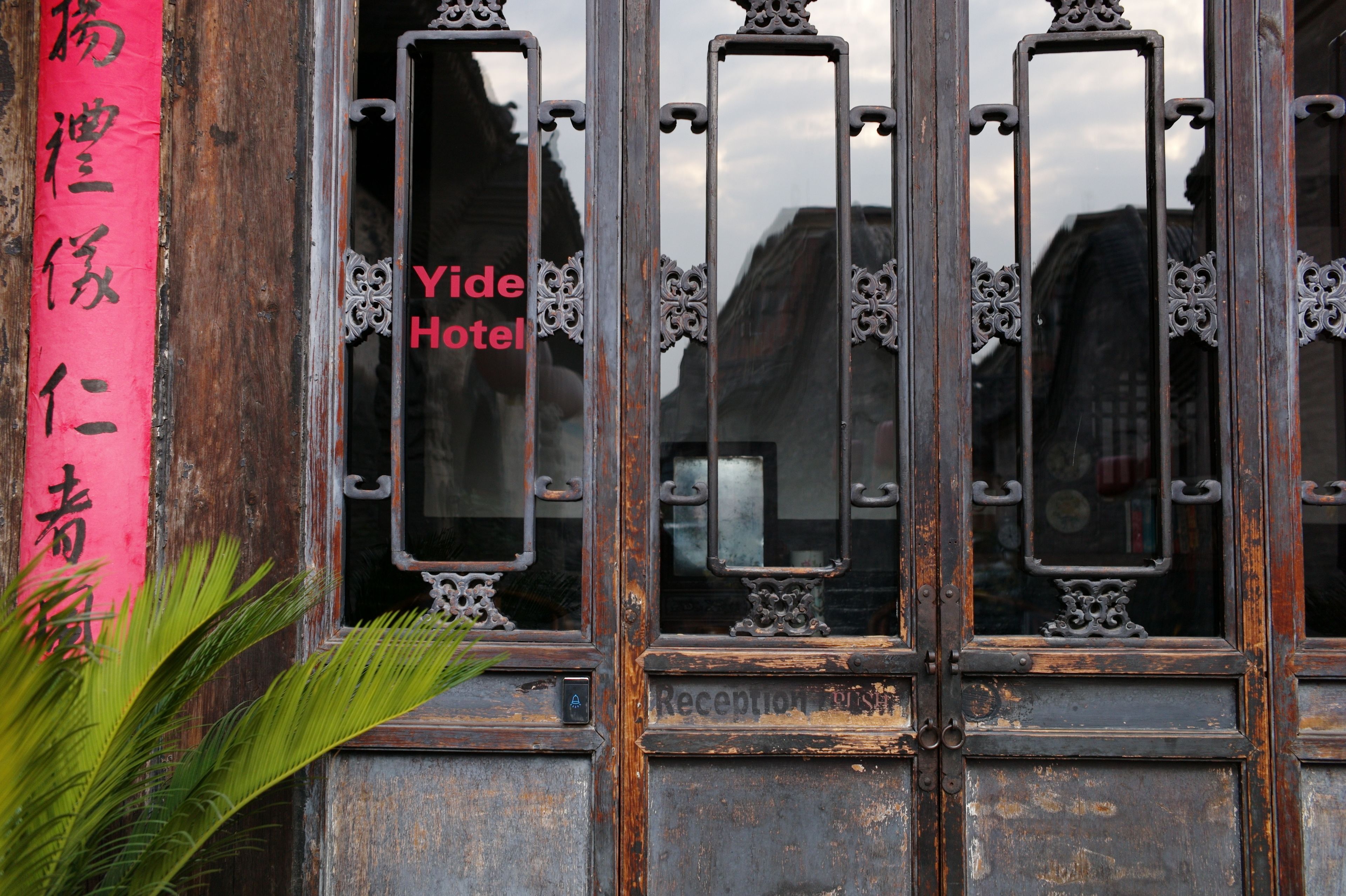 Uma porta de madeira tradicional com uma área de recepção e uma placa com o texto "Yide Hotel".