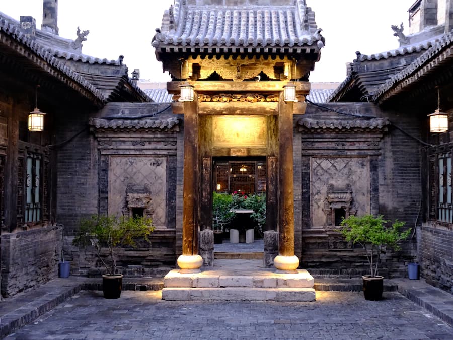 Un bâtiment traditionnel chinois doté d’une entrée centrale, flanqué de deux autres bâtiments présentant un style architectural similaire.