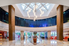 A spacious lobby with a high ceiling, a central floral arrangement, and a modern chandelier. - Chinflux Mandarin Hotel (Dongguan)