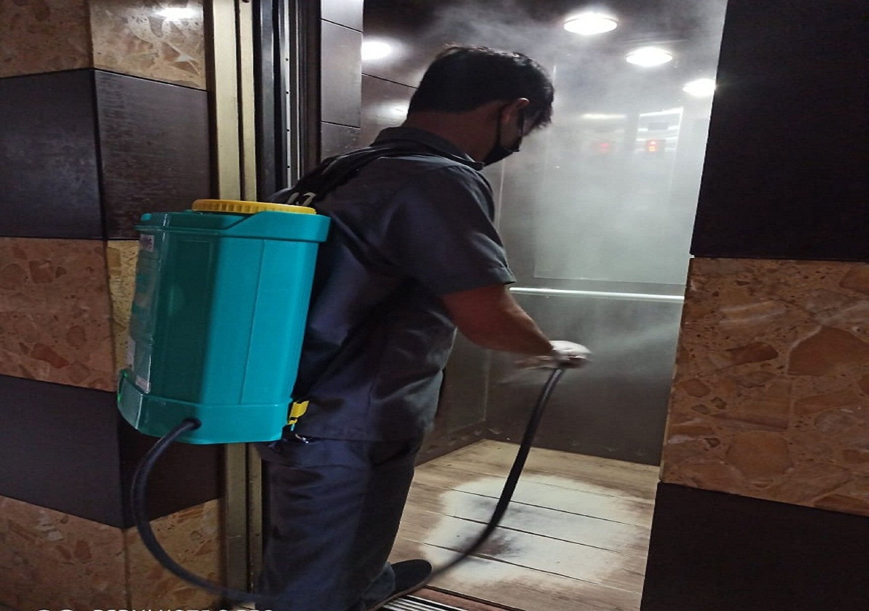 A person using a steam cleaner in a tiled room with a metal vent.