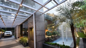 Un bâtiment moderne avec une façade en verre, une fontaine et une voiture garée à l’extérieur.