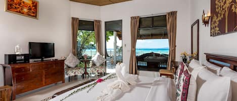 Habitación de hotel con cama, televisor, cómoda de madera y vista al océano.