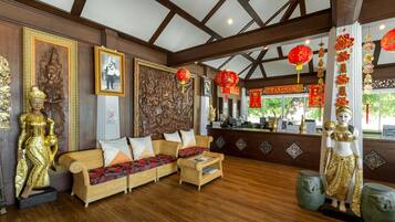 A traditional interior with wooden beams, a sofa set, and decorative statues.