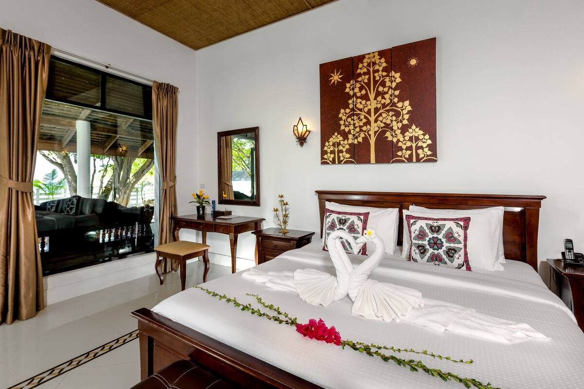 A hotel room with a large bed, a desk, a chair, and a view of the outdoors.