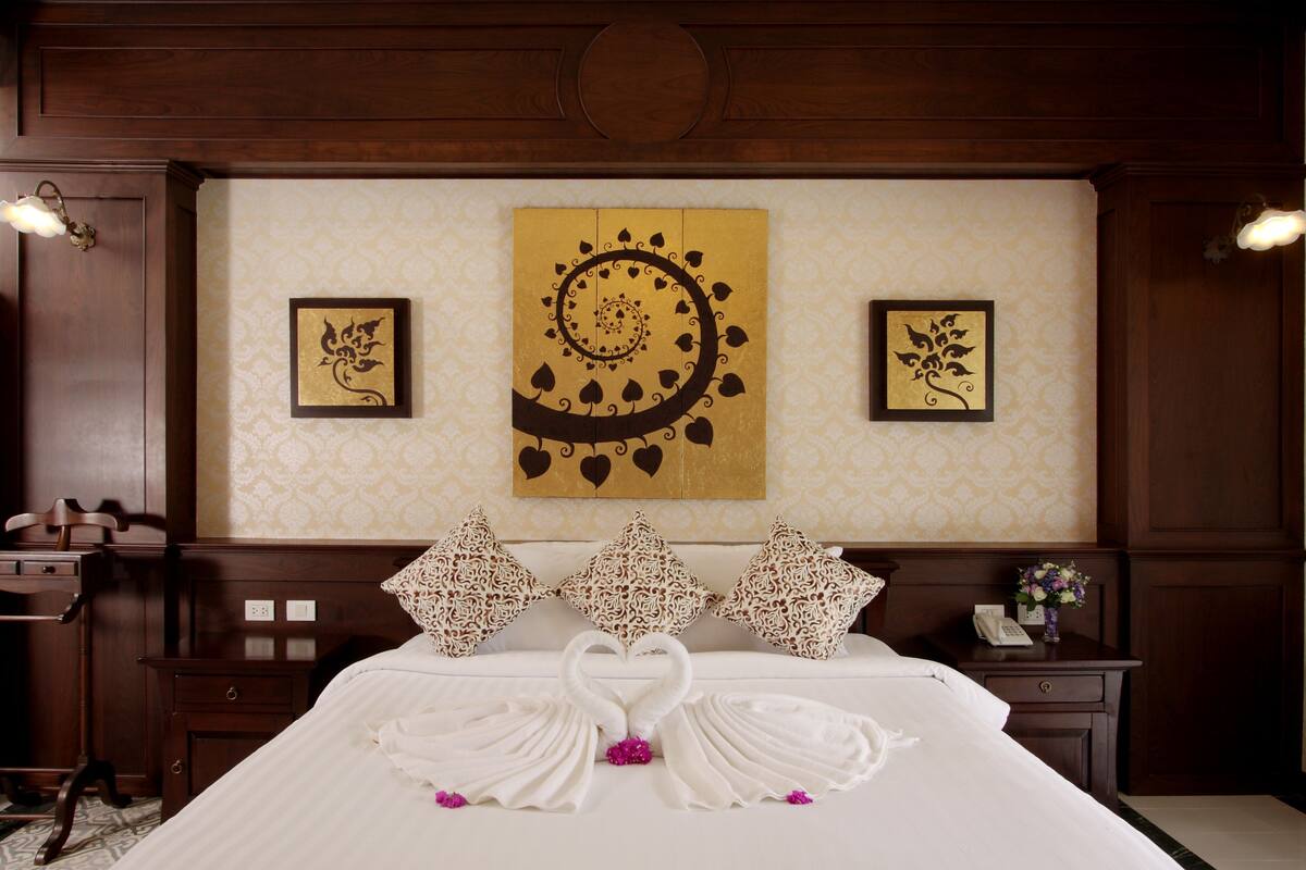 A hotel room with a neatly made bed, decorative pillows, and artwork on the wall.