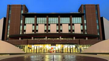 A modern building with a curved entrance, large glass windows, and a brick facade.