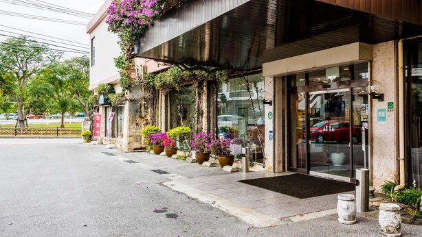 A hotel entrance with a modern design, featuring a glass door and a small outdoor seating area with planters. - Crown Hotel Okinawa (Okinawa)