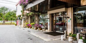 A hotel entrance with a modern design, featuring a glass door and a small outdoor seating area with planters. - Crown Hotel Okinawa (Okinawa)