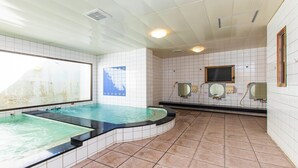 A spa area with a large bathtub, a smaller adjacent tub, and a window with a view of a mountain. - Crown Hotel Okinawa (Okinawa)