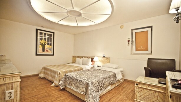 Une chambre d’hôtel avec un grand lit, un bureau, une chaise et un ventilateur de plafond.