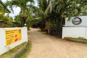 A sign for Bohol Sea Resort Dive Center with a dirt path leading to a gated entrance. - Bohol Sea Resort (Panglao)
