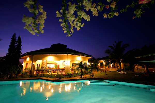 Una piscina al aire libre, sombrillas, sillones reclinables de piscina