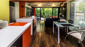 A modern kitchen with a dining area, large windows, and a view of greenery. - Corinda Contemporary (Glebe)