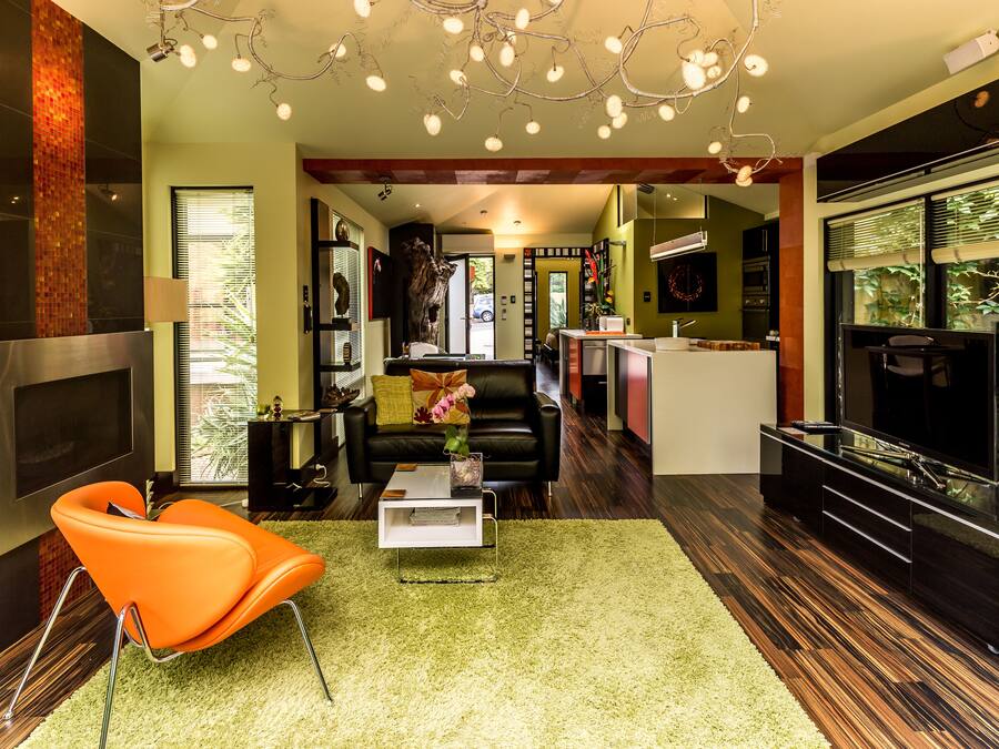 Een moderne woonkamer met een bank, salontafel en een televisie. Achtergrond is een keuken met een eettafel en stoelen.