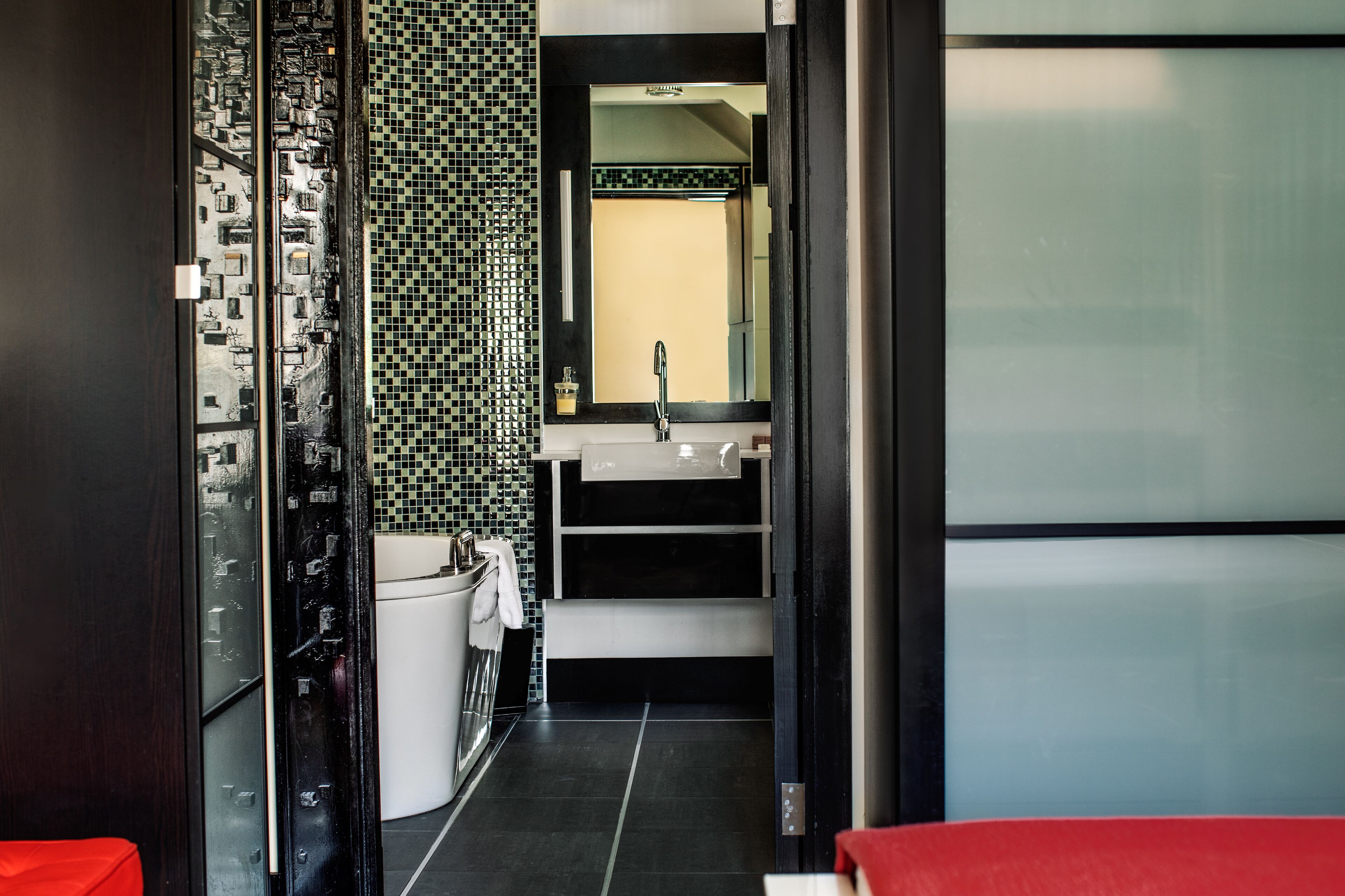 A modern bathroom with a black and white tiled wall, a white sink, and a mirror above it.